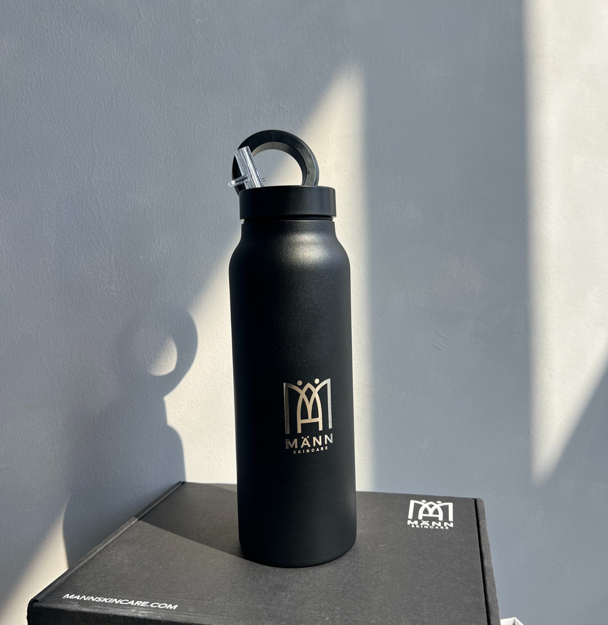Black water bottle with a logo on a gray surface